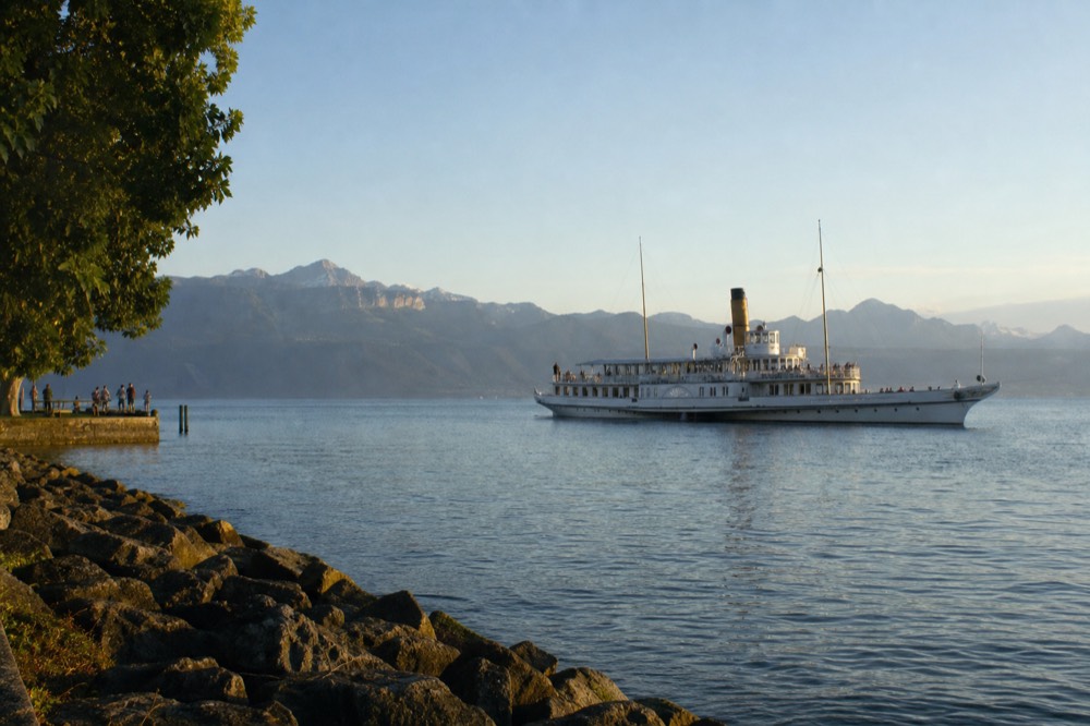 A CGN cruise boat on Lake Geneva near Vevey on a clear summer morning, deep blue water and the Alps on the far shore