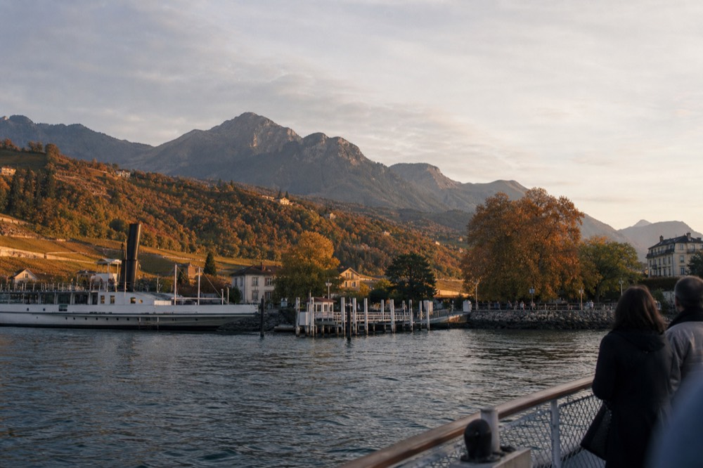 The Château de Chillon landing stage at Veytaux on Lake Geneva seen from an approaching boat, the Alps behind