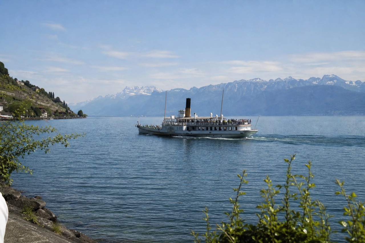 A CGN cruise boat on Lake Geneva off Montreux, the Swiss Riviera shoreline and the Alps across the water