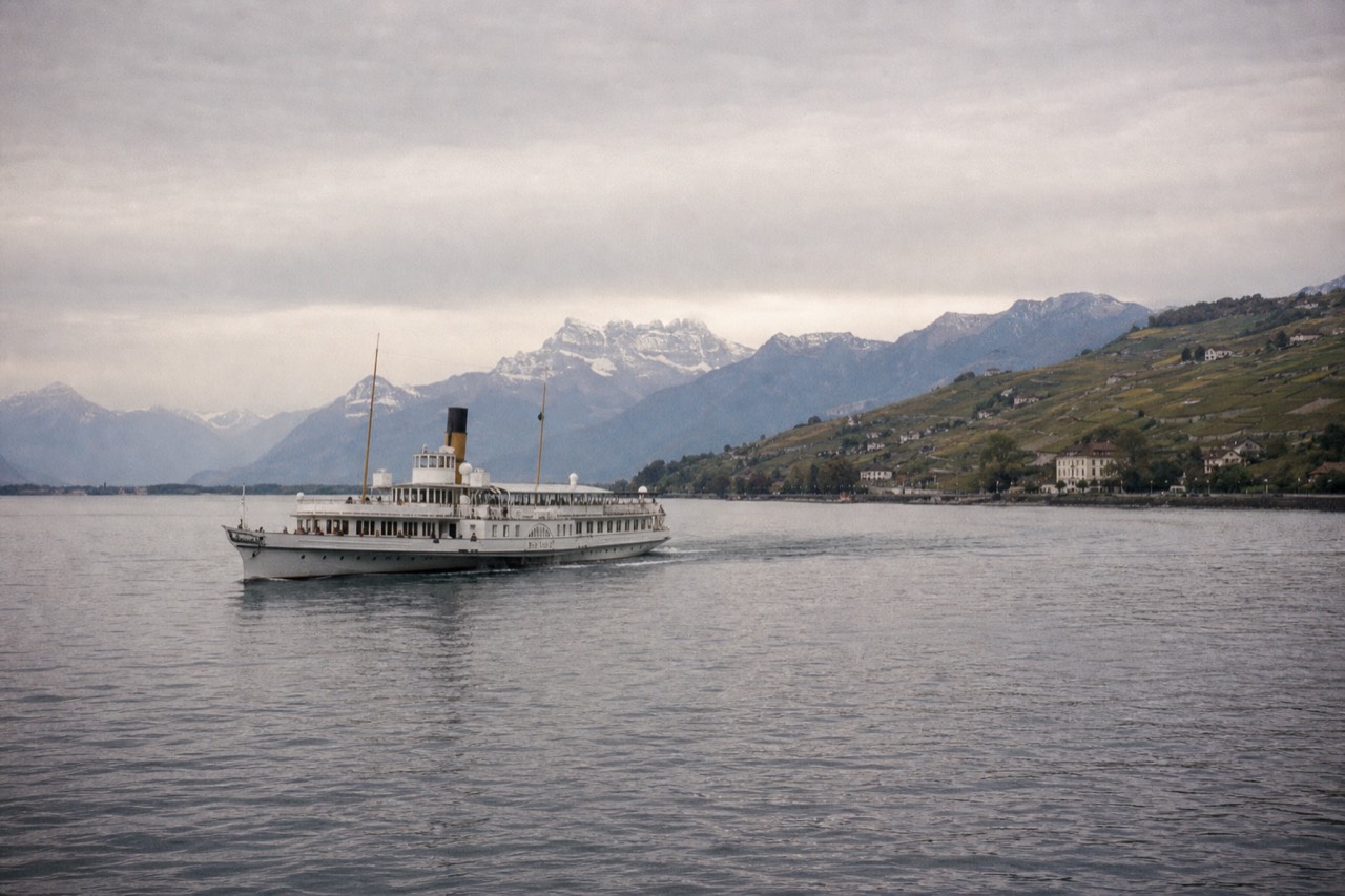A CGN cruise boat on Lake Geneva near Montreux, the Alps across the water and vineyard slopes along the Swiss shore