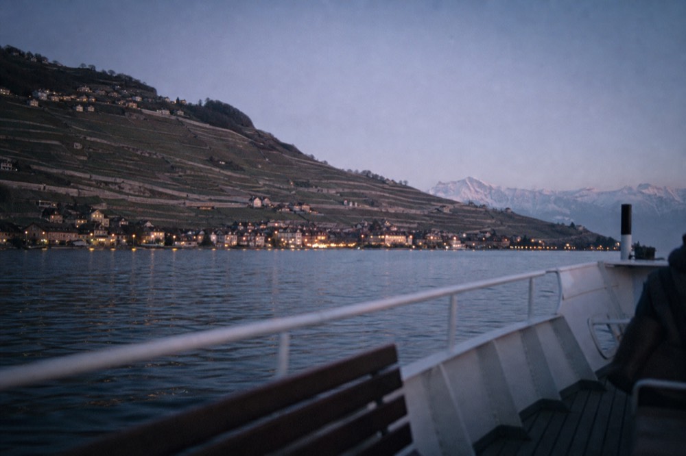 View from a boat deck of the Lavaux vineyard terraces climbing above Lake Geneva near Vevey, the Alps across the water