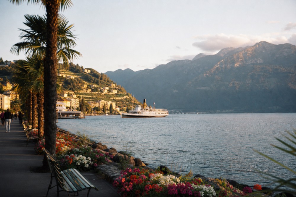 The flower-lined lakeside promenade at Montreux on Lake Geneva, palm trees and benches along the water with mountains across the lake