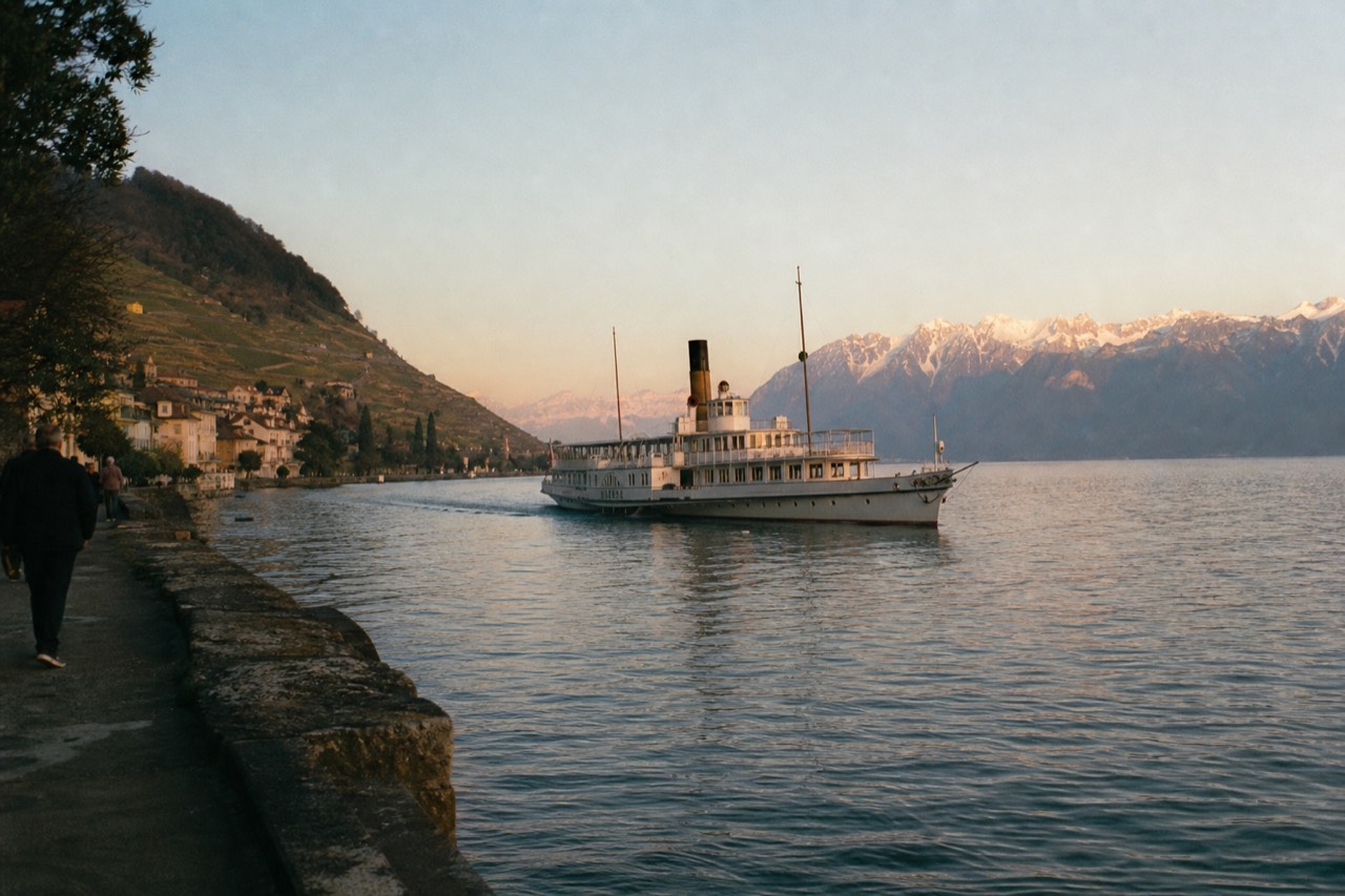 The Swiss shore of Lac Léman near Montreux, vineyard terraces above the water and the Alps rising across the lake