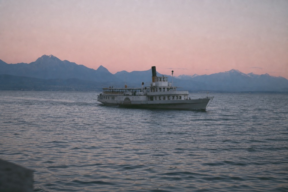 A plain-hulled CGN passenger ferry mid-lake on Lake Geneva between Nyon and Yvoire, the French shore ahead