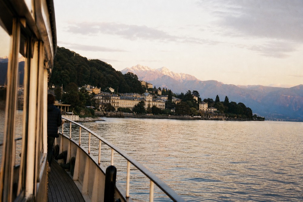 Approaching the French lakeshore town of Évian-les-Bains from a boat on Lake Geneva, wooded hills and lakefront buildings ahead