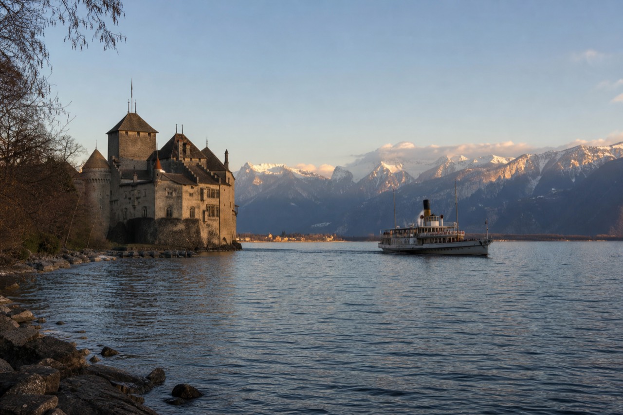 Château de Chillon on its rock island near Montreux on Lake Geneva, the Alps rising across the water and a CGN boat approaching the landing stage