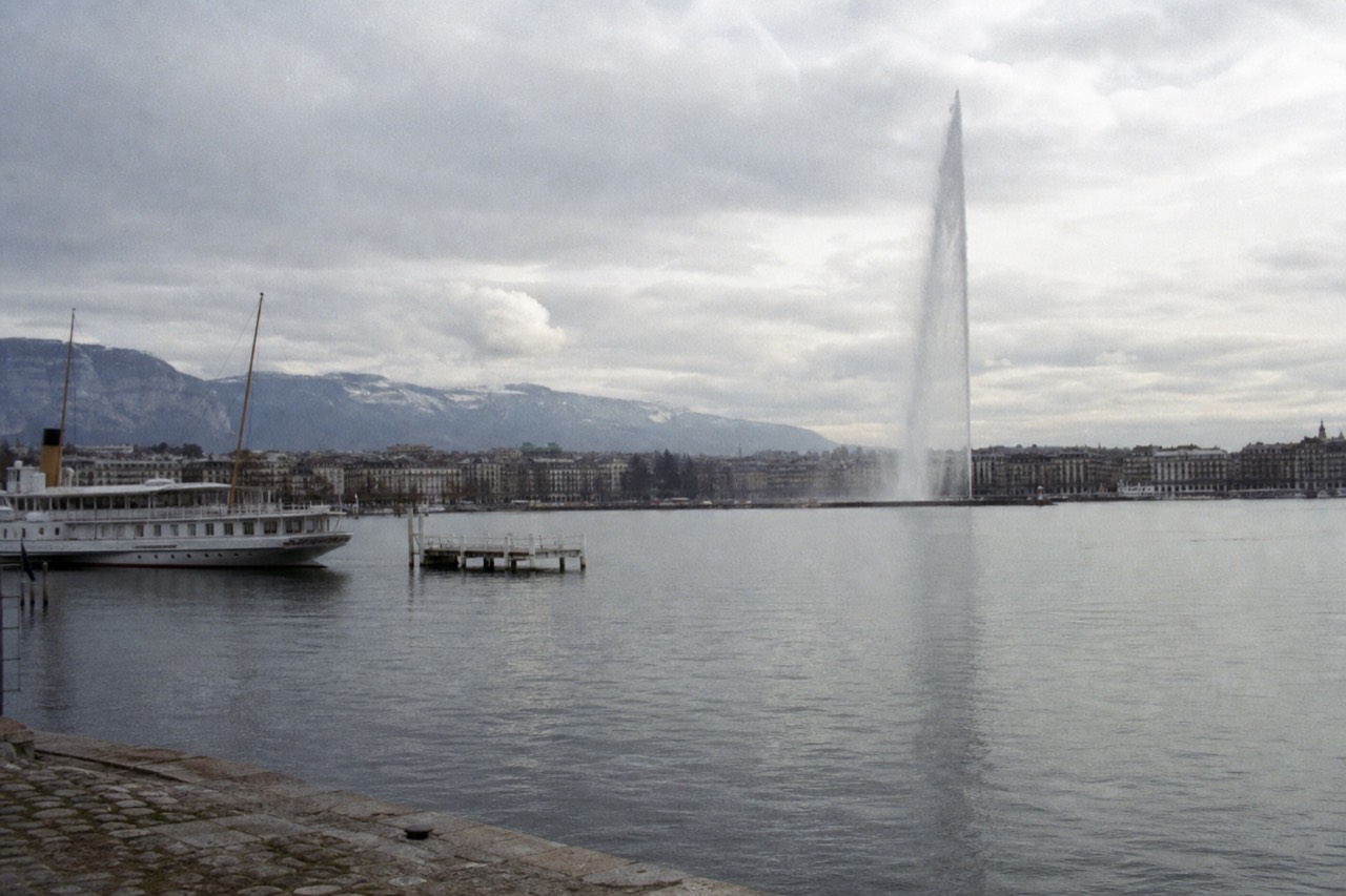 The Jet d'Eau fountain in Geneva harbour on Lac Léman, the city waterfront and the Alps in the distance