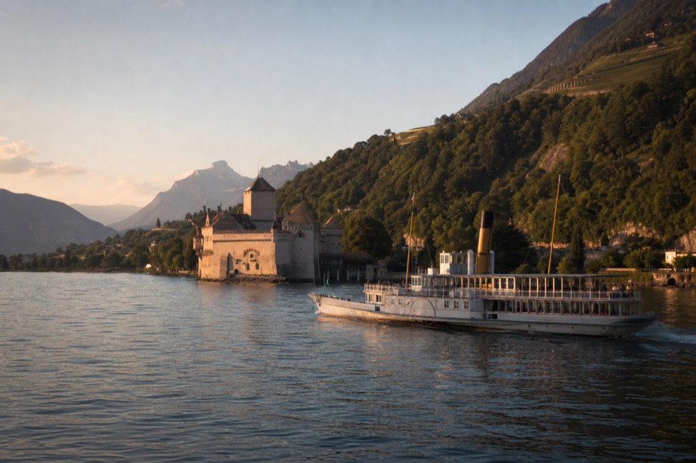 A Belle Époque paddle steamer passing Château de Chillon on Lac Léman in summer light