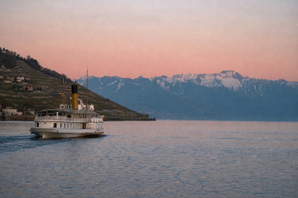 A CGN boat on the Riviera stretch of Lake Geneva near Montreux, vineyards on one side and the Alps across the water