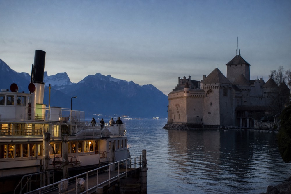 Château de Chillon rising off the shore of Lake Geneva near Montreux, a CGN boat at the landing stage and the Alps behind