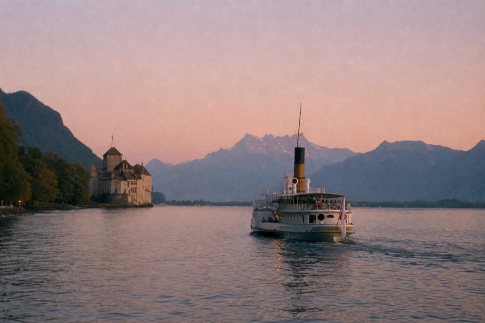 A CGN boat on the Riviera stretch of Lake Geneva near Montreux, the Château de Chillon and the Alps in the distance