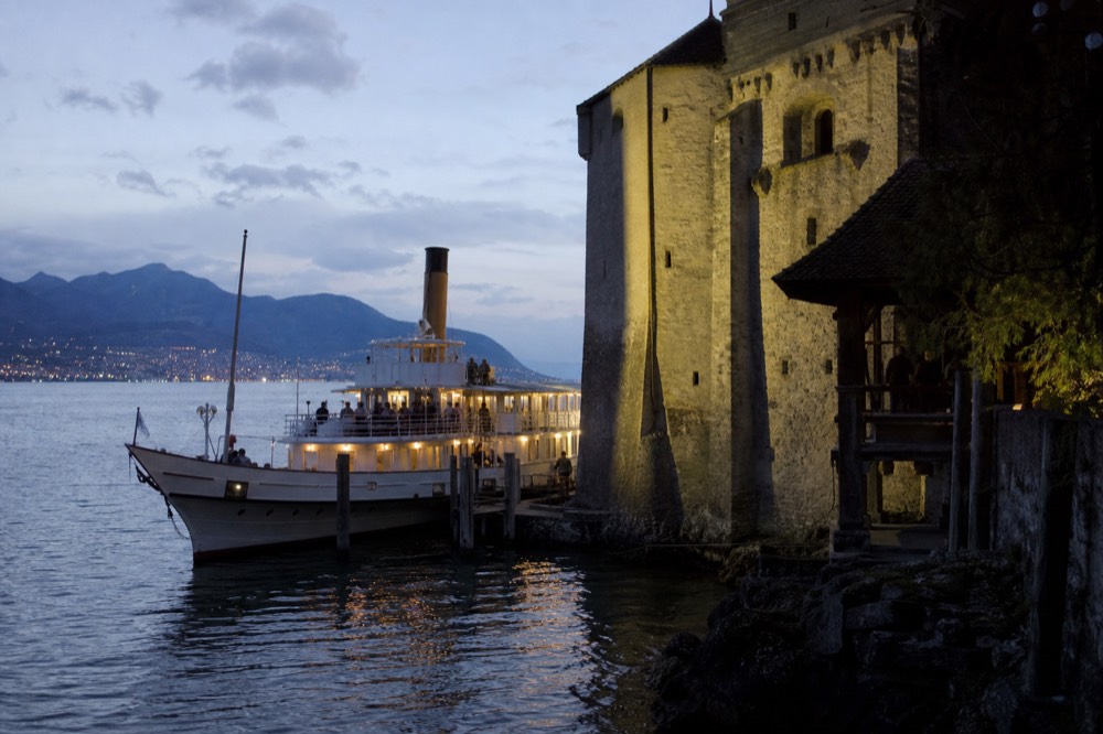 A CGN boat at the Château de Chillon landing stage on Lake Geneva, the castle walls rising straight off the water