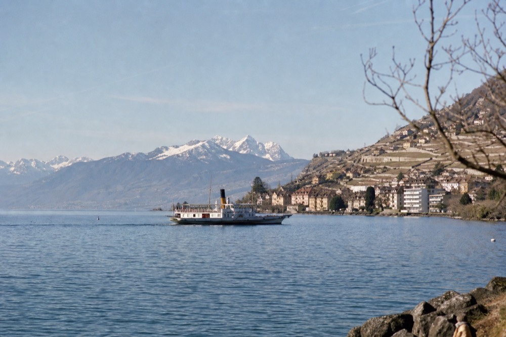 A CGN boat off the Vevey shoreline on Lake Geneva, the town waterfront and the Lavaux terraces behind