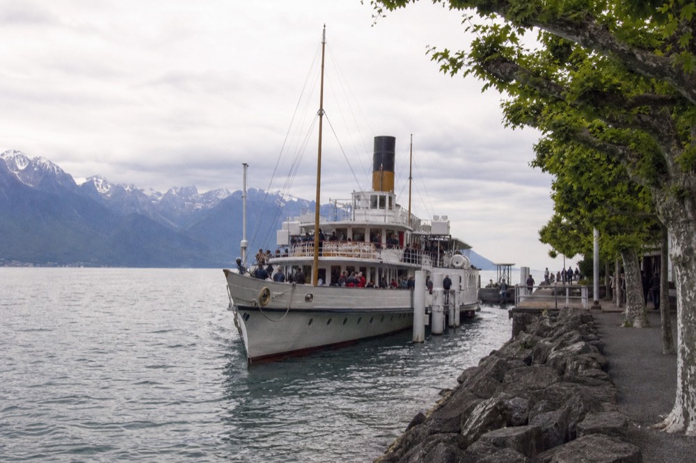 A CGN scheduled boat calling at a Lake Geneva pier with the Alps across the water