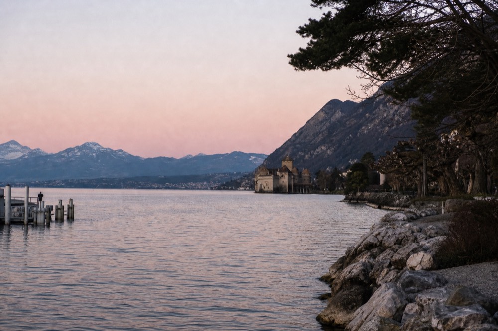 The Montreux Riviera shoreline on Lake Geneva with Château de Chillon in the distance and the Alps across the water