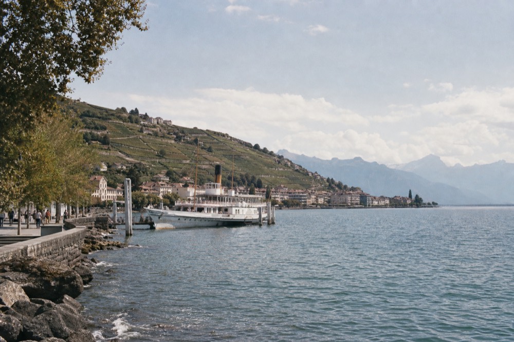 The Vevey lakefront on Lake Geneva with a cruise boat at the quay and the Alps across the water