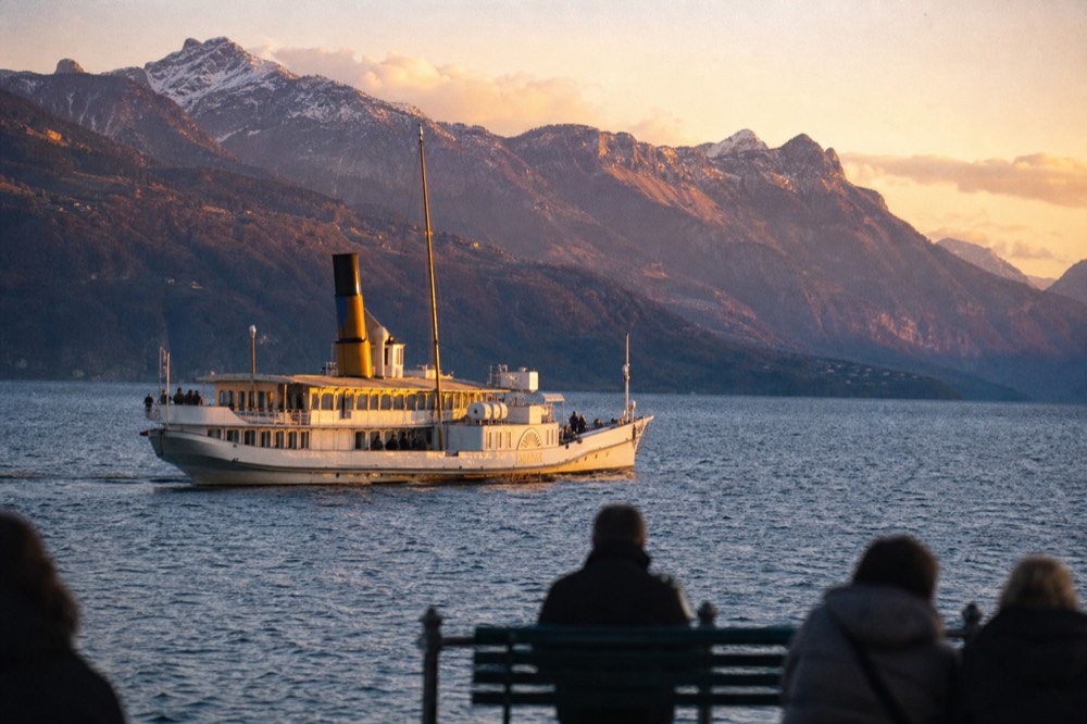 A Belle Époque paddle steamer on the Riviera water of Lake Geneva near Montreux with the Alps across the water