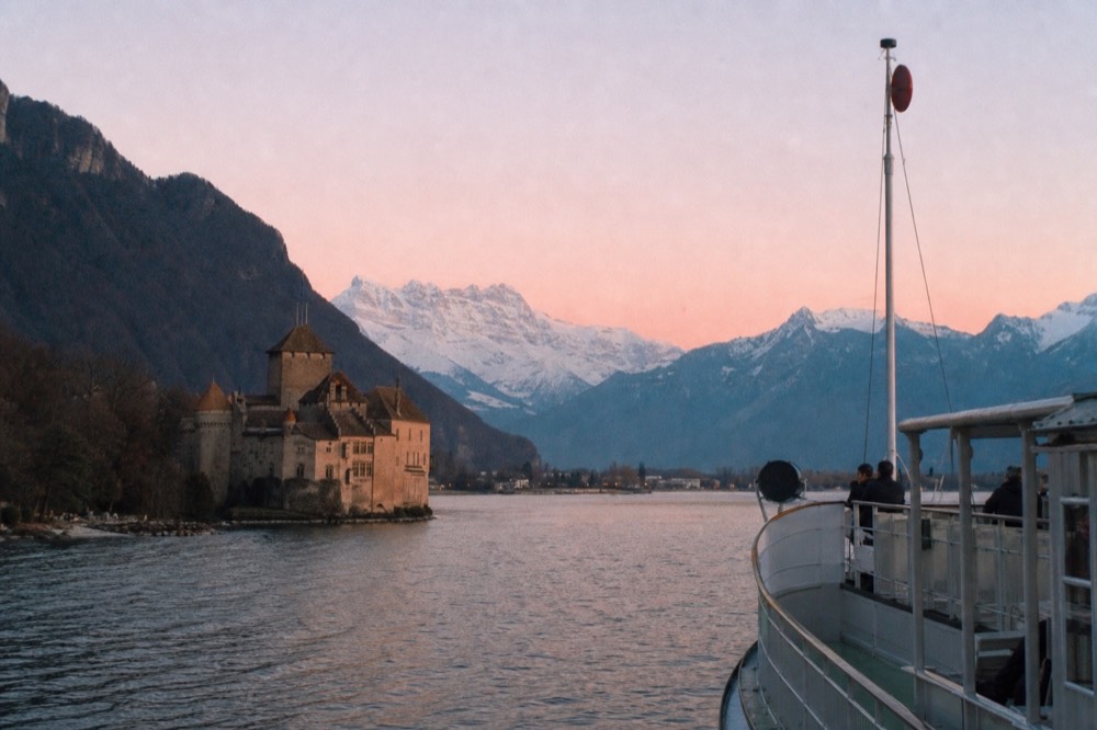 Château de Chillon on the shore of Lake Geneva east of Vevey, seen from a cruise boat with the Alps behind