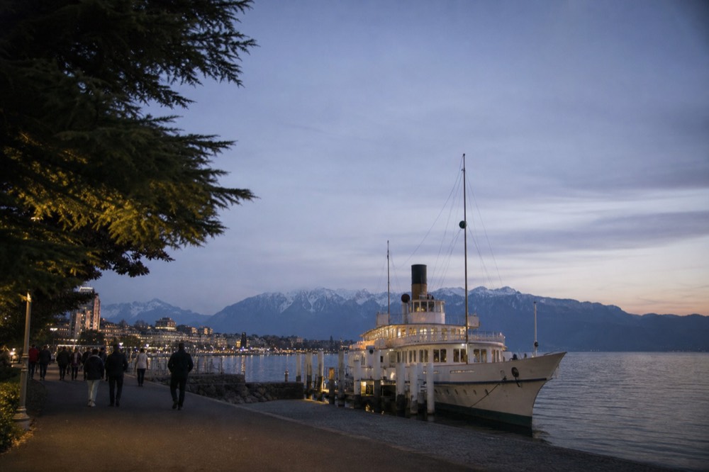 A cruise boat at the Vevey quay on Lake Geneva at golden hour with the Alps across the water